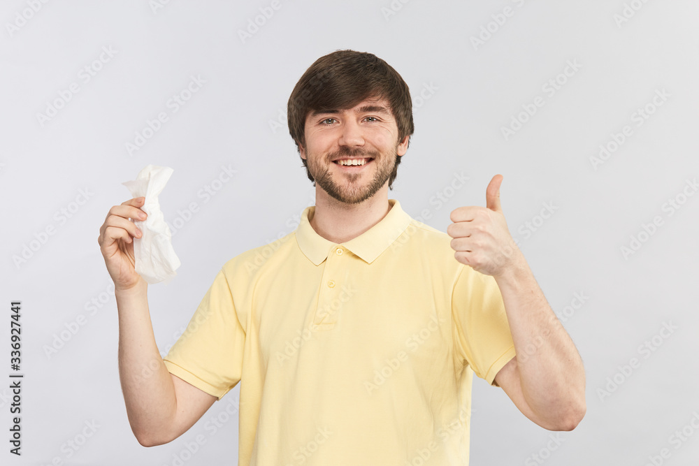 handsome young man holding napkin for self care while virus and showing thumds up gesture with big smile on his face handsome young man holding napkin for self care while virus and showing thumds up gesture with big smile on his face