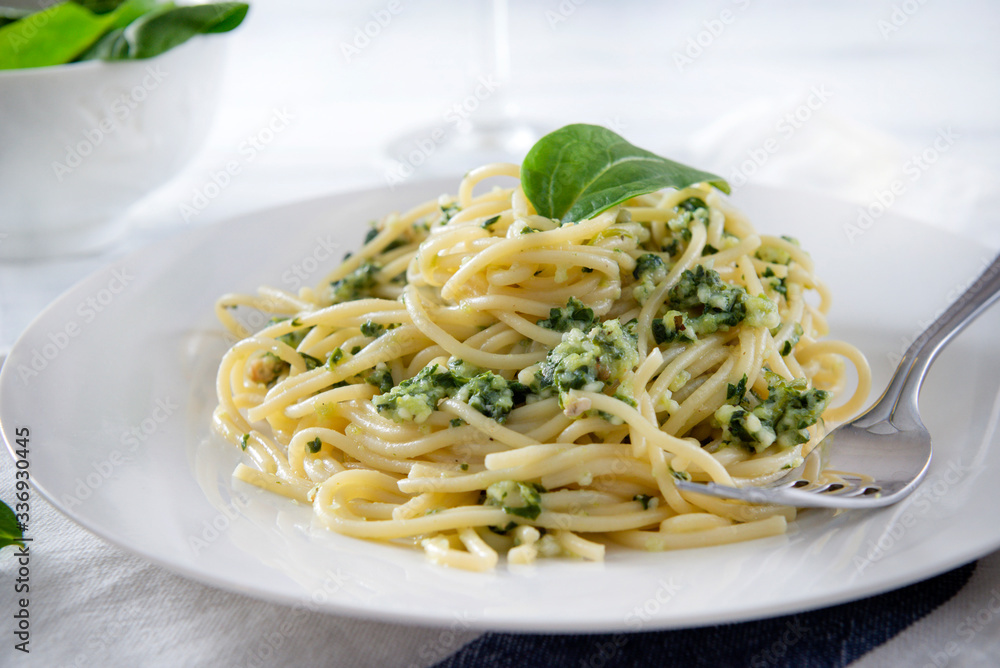 plate of pasta, spaghetti with spinach on a white wooden close-up plate of pasta, spaghetti with spinach on a white wooden close-up