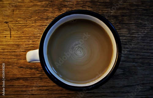 stir latte in a black and white cup in a wooden background