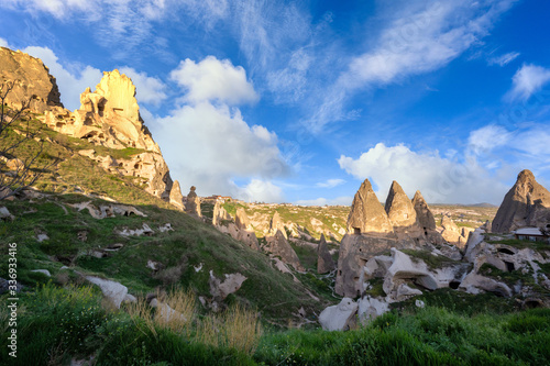 Uchisar Castle and the town are sandstone mountains filled with tunnels and windows. In the morning, the sun hits the golden peaks and blue skies of Cappadocia, Turkey.
