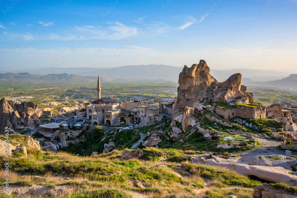 The landscape of cappadocia, Turkey. The view from the top of the hill overlooks the Uchisar Castle and this old town is a sandstone mountain. In summer, there are green grass and blue skies.