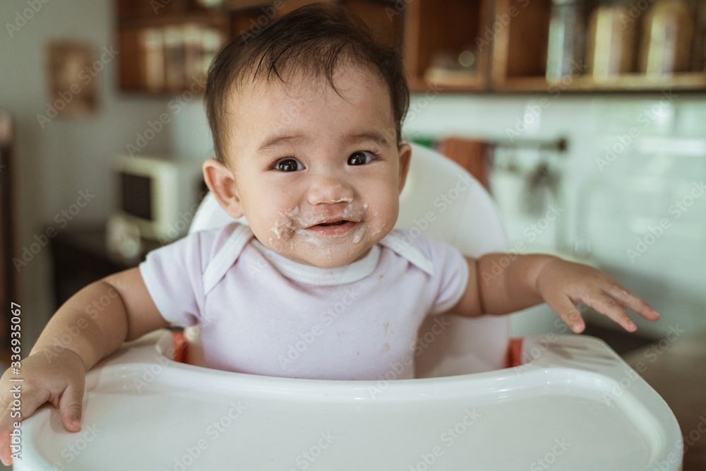 happy asian baby feeding time sitting on highchair happy asian baby feeding time sitting on highchair