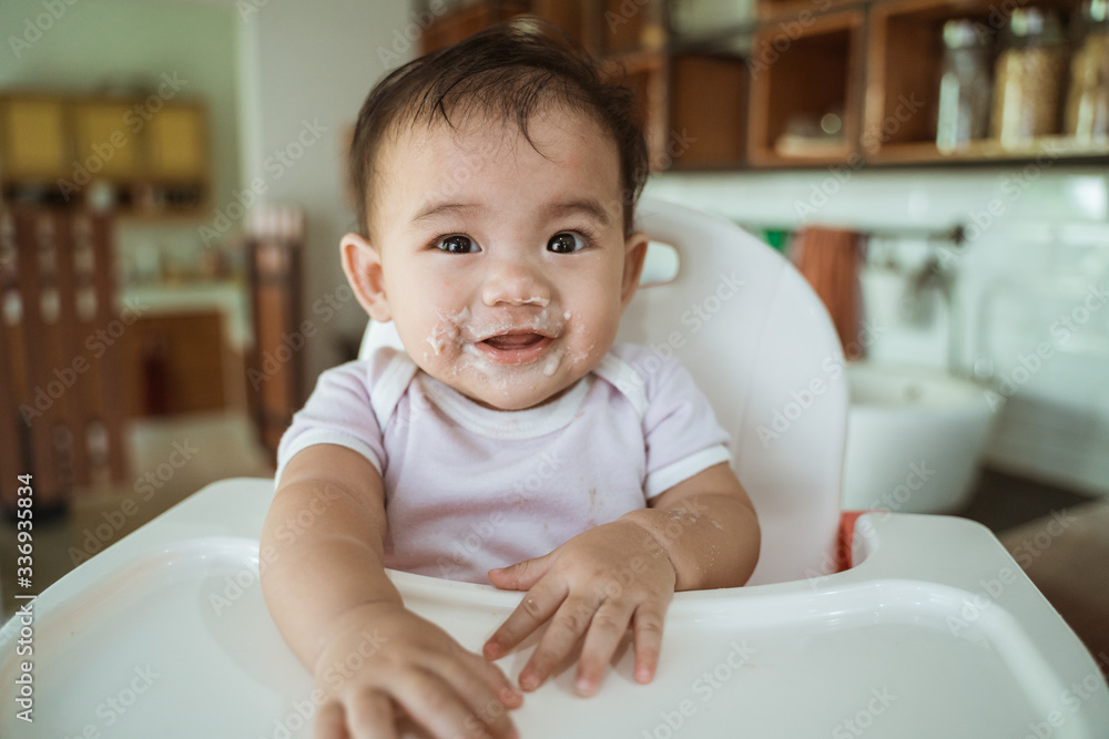 happy asian baby feeding time sitting on highchair happy asian baby feeding time sitting on highchair