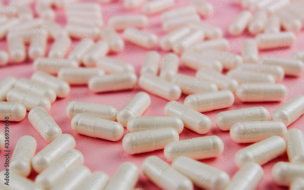 White pills on a pink background. Scattered tablets. White pills on a pink background. Scattered tablets.