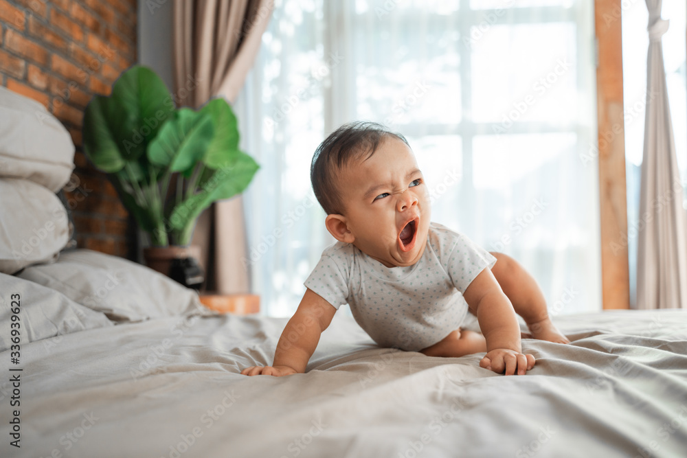 Fototapeta premium asian baby learn to crawl on the bed. crawling development milestone