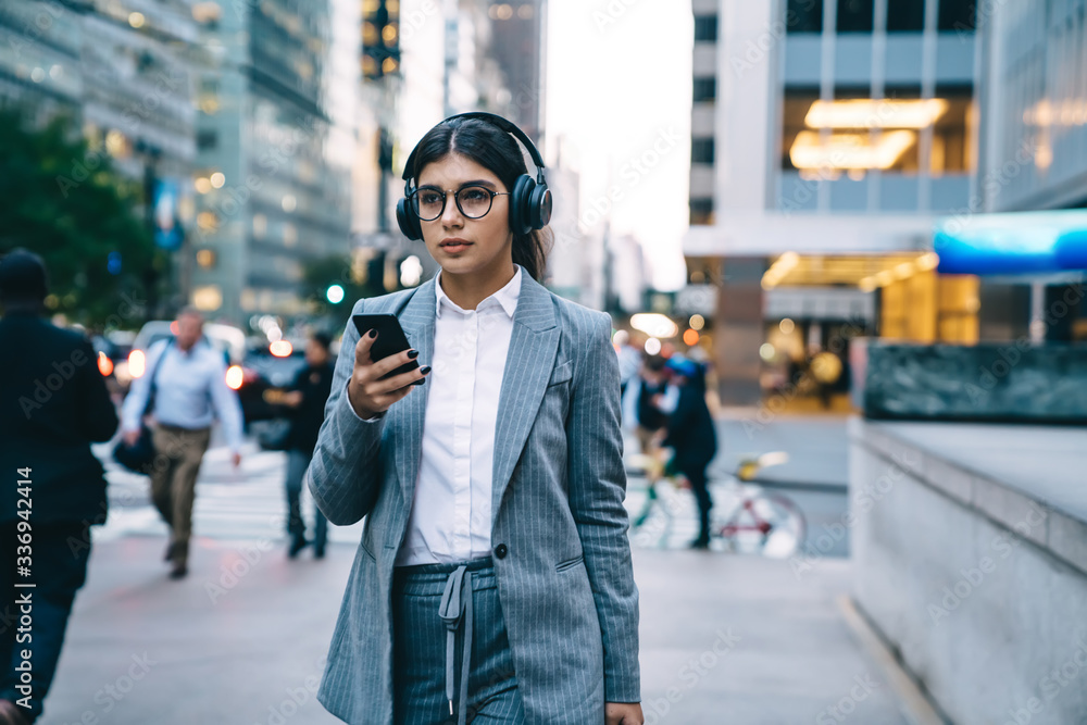 Businesswoman walking in downtown and using smartphone Businesswoman walking in downtown and using smartphone