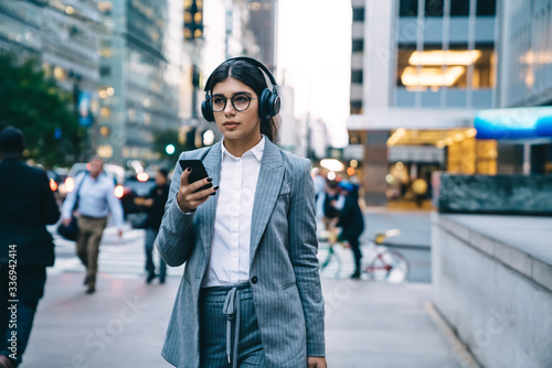 Businesswoman walking in downtown and using smartphone