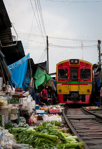 A thailand train going in the middle of a train market