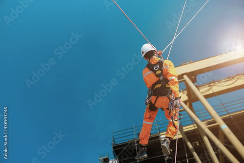 Rope access Safety sprinkling worker on high with scaffolding wearing dresses and safety man with full harness safety concept in site construction building on tower crane background.