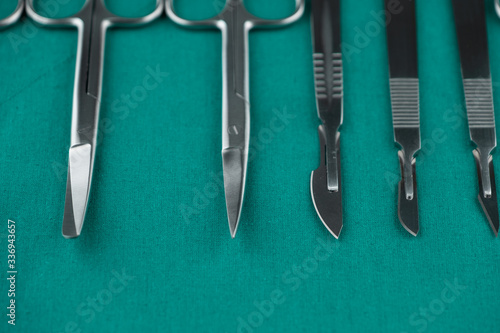 Basic surgical instrument scalpel forceps tweezers scissors on surgical green drape fabric in operation room