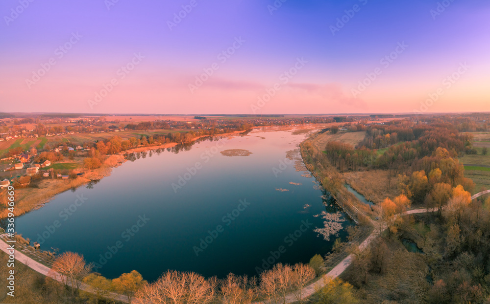 Spring rural landscape in the evening, aerial view. Panoramic view of the village and lake during sunset. Panorama from 9 images