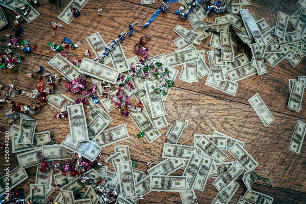 Many dollar bills scattered on a wooden floor