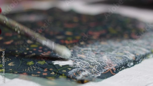 Close up: woman's hand and brush applying glue on material, decoupage