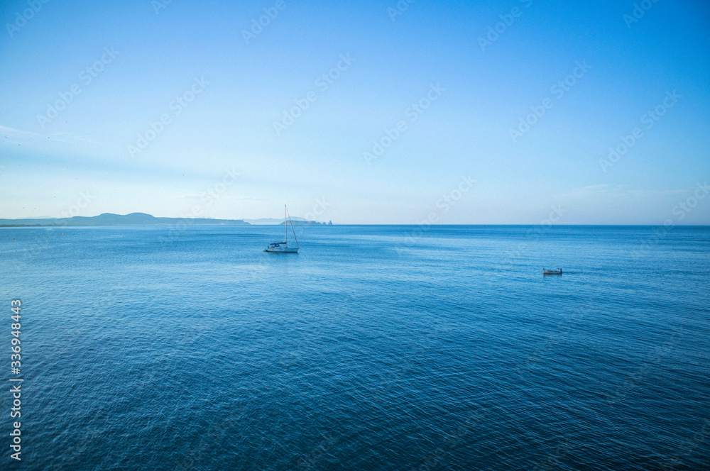 Seascape with two little boats in the middle of the mediterranean sea on sunset