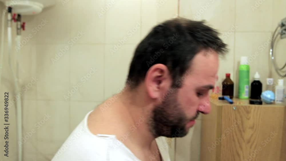 a sleepy man enters the bathroom and begins to wash his face funny, rinse his mouth, brush his teeth, bend over, get up, look at himself in the mirror. in profile, close-up, full hd, no sound. a sleepy man enters the bathroom and begins to wash his face funny, rinse his mouth, brush his teeth, bend over, get up, look at himself in the mirror. in profile, close-up, full hd, no sound.
