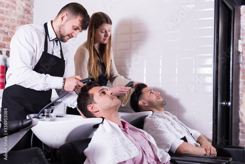 Hairdressers washing hair of clients
