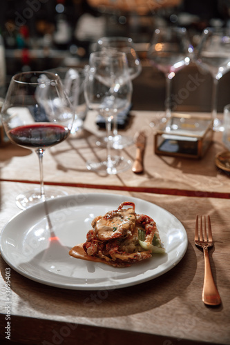 Wooden table with food and drink in a restaurant. Dish and glasses of wine. Chamber light. Soft focus