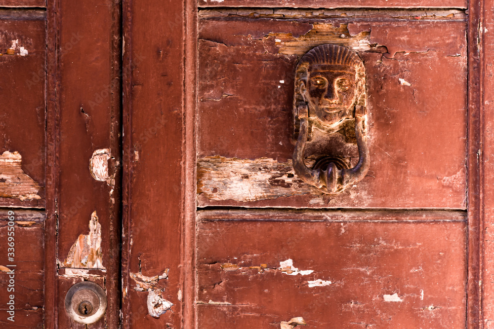 Detail of an old, weathered and rustic door with a rusty, Egyptian themed door knocker
