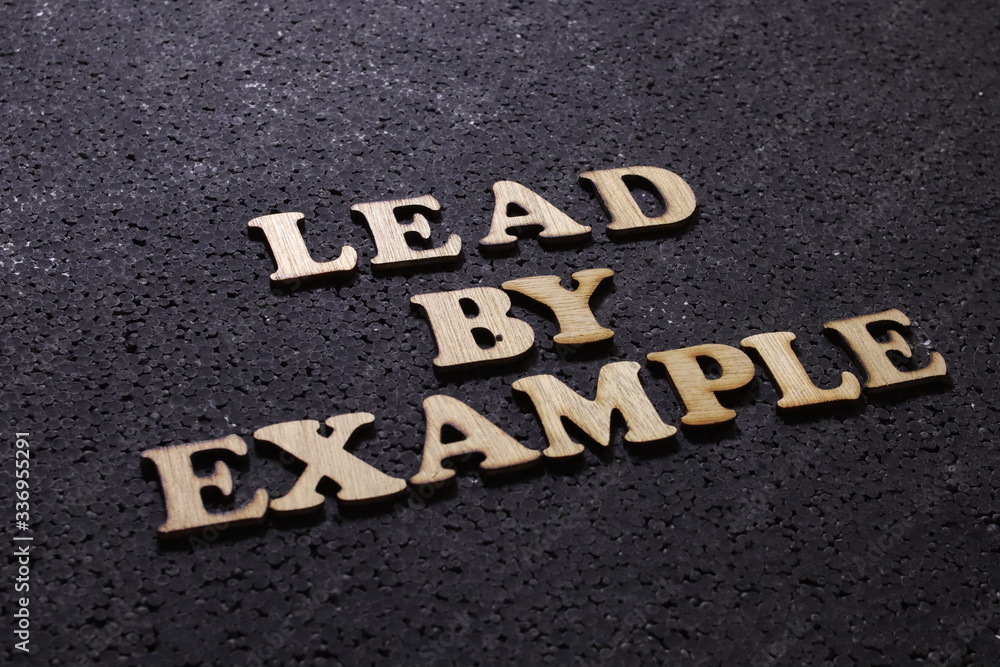 Lead by example, business motivational inspirational quotes; wooden words typography lettering concept Lead by example, business motivational inspirational quotes; wooden words typography lettering concept
