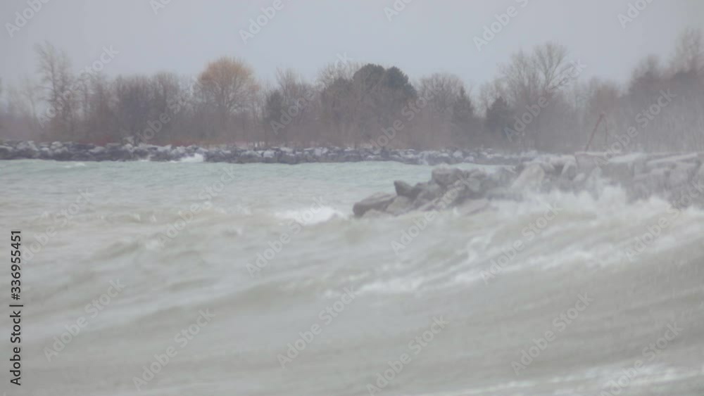 Big Waves Splashing To The Rocky Shore In The Ocean In Canada With Bare Trees In The Background - Medium Shot Big Waves Splashing To The Rocky Shore In The Ocean In Canada With Bare Trees In The Background - Medium Shot