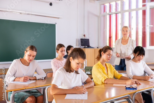 Students writing in notepads during lesson © JackF