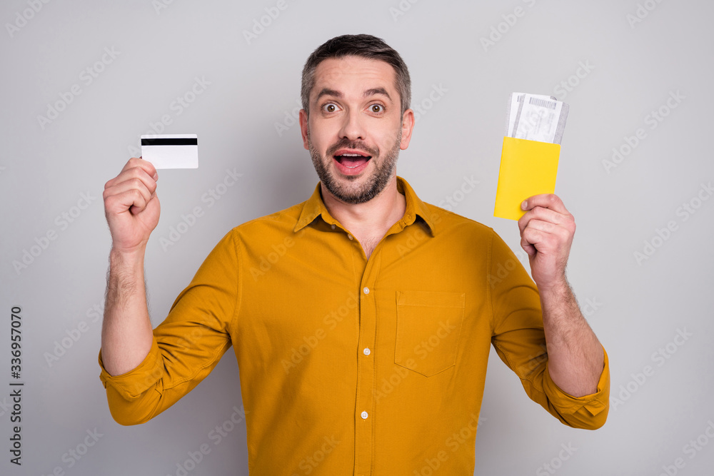 Portrait of surprised crazy mature man hold tickets vise credit card impressed easy banking payment tourism resort scream wow omg wear yellow outfit isolated over gray color background Portrait of surprised crazy mature man hold tickets vise credit card impressed easy banking payment tourism resort scream wow omg wear yellow outfit isolated over gray color background