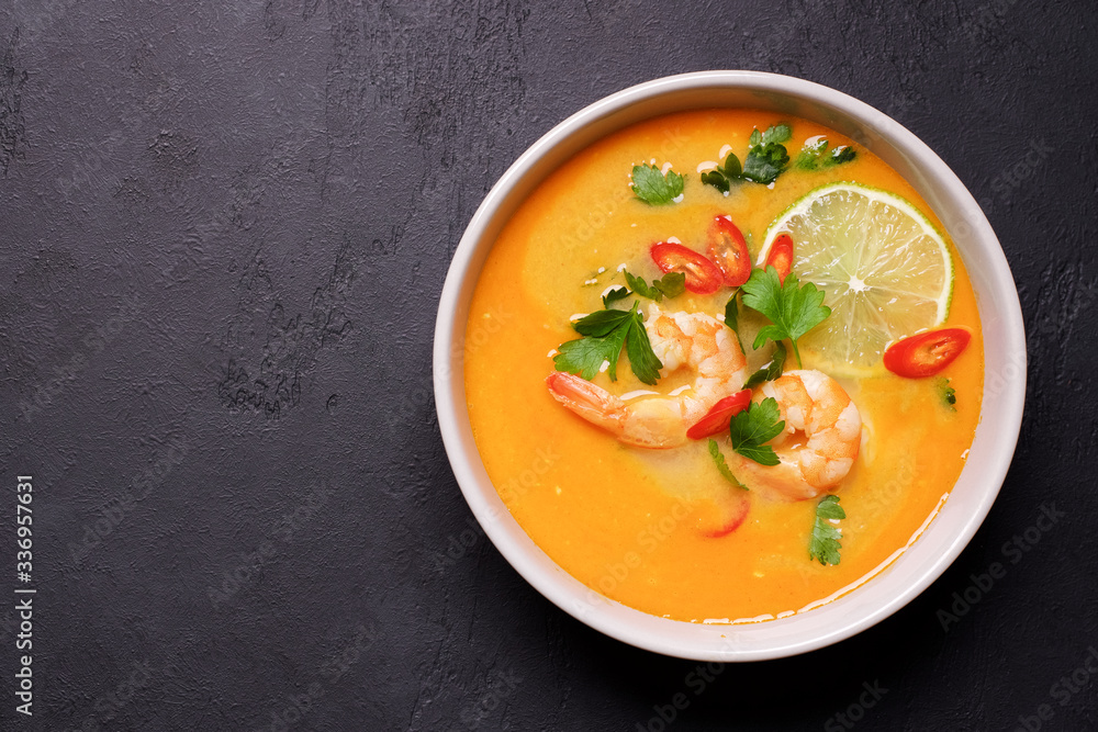 Tom Yam kung Spicy Thai soup with shrimp, coconut milk and chili pepper in bowl. Black stone background Tom Yam kung Spicy Thai soup with shrimp, coconut milk and chili pepper in bowl. Black stone background