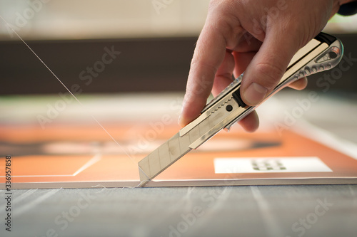 Close-up of hand with skalpel. Worker cut paper in printshop photo