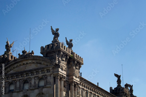 Close up view of historical winged lion sculptures on top of old building in Barcelona. It is a sunny summer day.