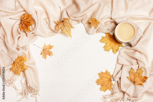 Top view of cup coffee cappuccino with milk foam   warm fabric scarf  yellow autumnal season leaves of maple tree on white wooden table with copy space. Time for relax.