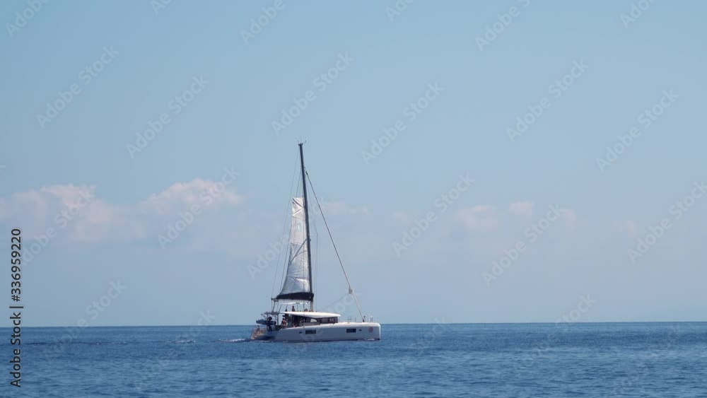 White sailing boat with tourists on board floating across Mediterranean sea. Lipari Islands. Sicily, Italy. Horizon, blue sky White sailing boat with tourists on board floating across Mediterranean sea. Lipari Islands. Sicily, Italy. Horizon, blue sky