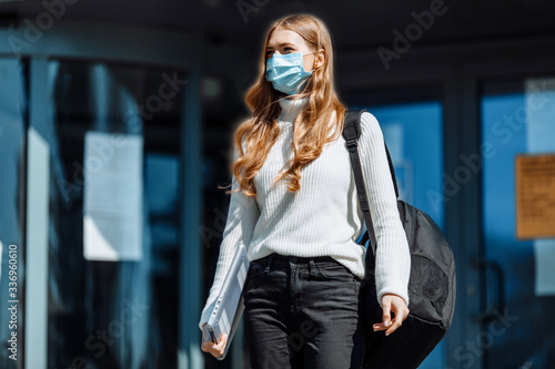 Beautiful young girl in a mask from coronovirus, student on the background of educational envy, women returning from work