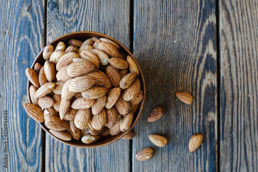 Almonds in the wooden bowl on the table, close-up Almonds in the wooden bowl on the table, close-up