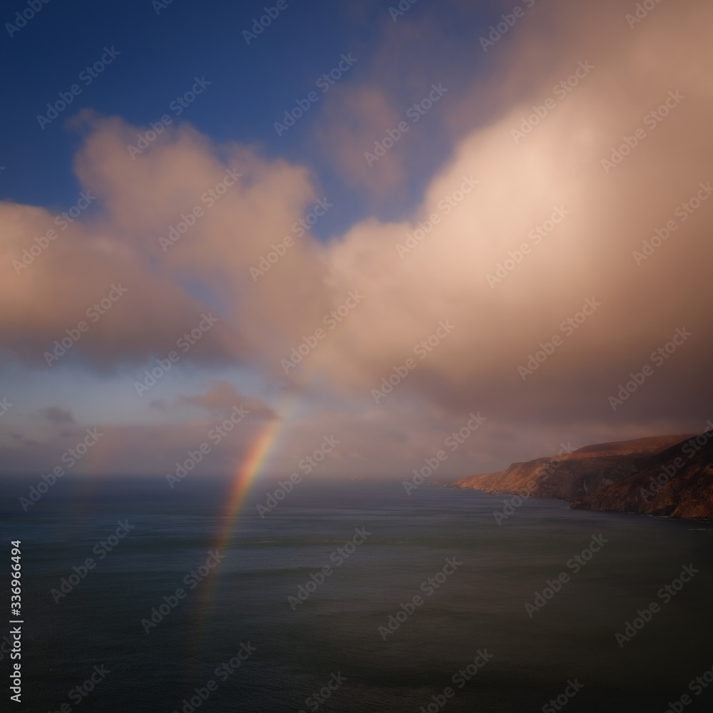 Epic view of Atlantic ocean cliffs under heavy clouds with rainbow, Slieve League, Donegal, Ireland