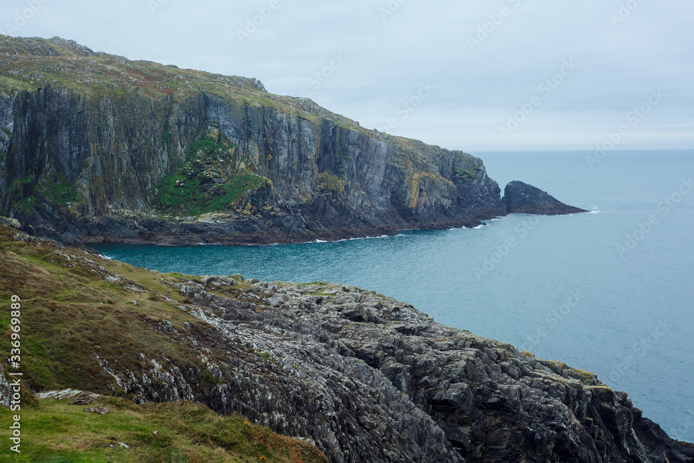 Green rocks on atlantic coast. Blue water and grey stones of Ireland
