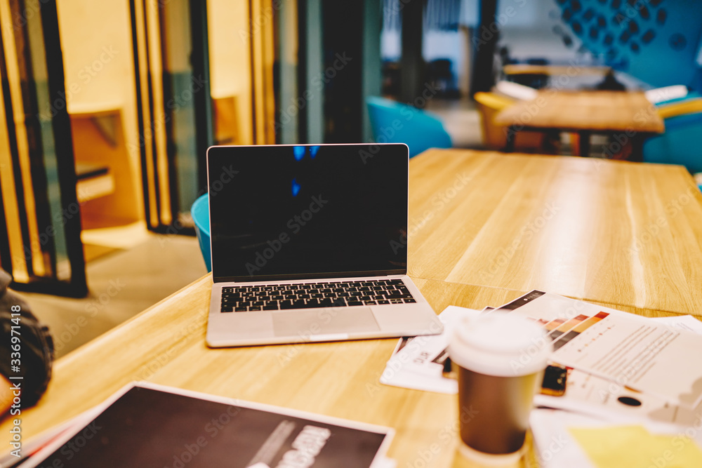 Selective focus on modern laptop computer with copy space area for your internet advertising, mockup digital netbook and paper documents for e learning standing on table desktop in coffee shop Selective focus on modern laptop computer with copy space area for your internet advertising, mockup digital netbook and paper documents for e learning standing on table desktop in coffee shop