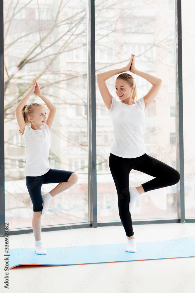 Naklejka premium Yoga pose with mother and smiling daughter at home