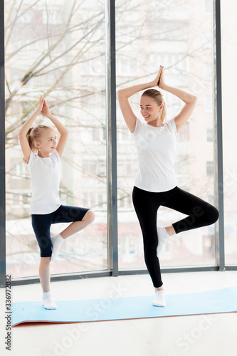 Yoga pose with mother and smiling daughter at home