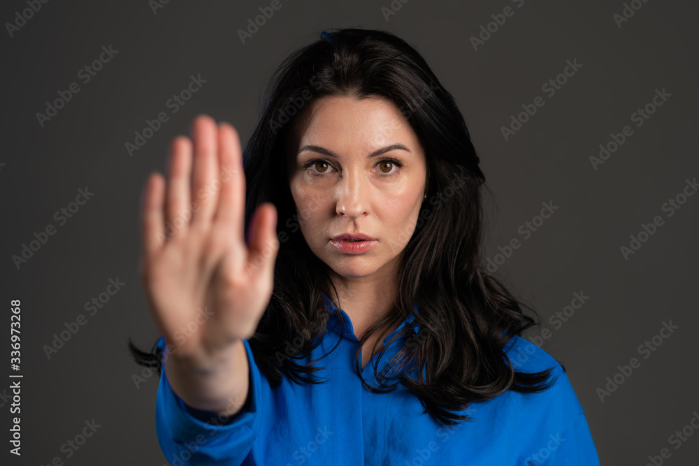 Adult woman disapproving with NO hand sign gesture. Denying, rejecting, disagree, portrait of beautiful lady on grey background Adult woman disapproving with NO hand sign gesture. Denying, rejecting, disagree, portrait of beautiful lady on grey background