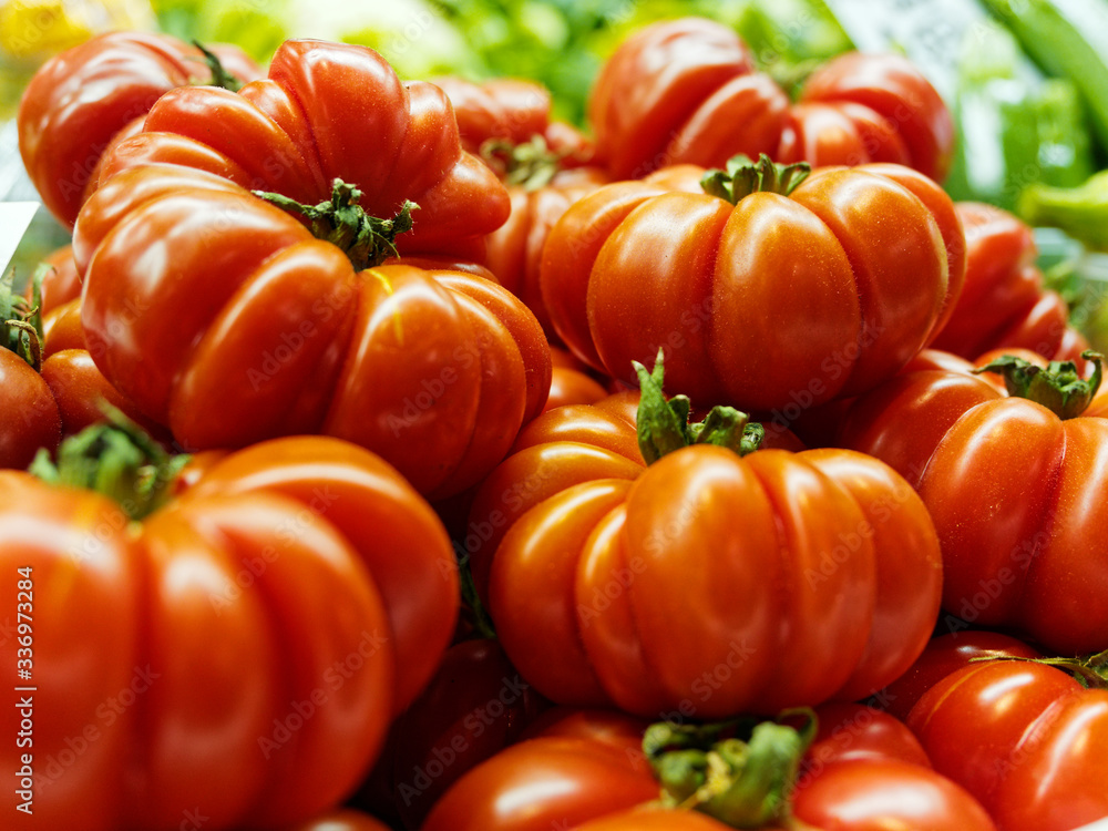 Red ribbed tomatoes lying on top of each other, close-up.