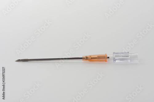 Orange intravenous cannula 14 G on white background, external diameter 2,1 mm, used in trauma, blood transfusion, surgery, ascites puncture.