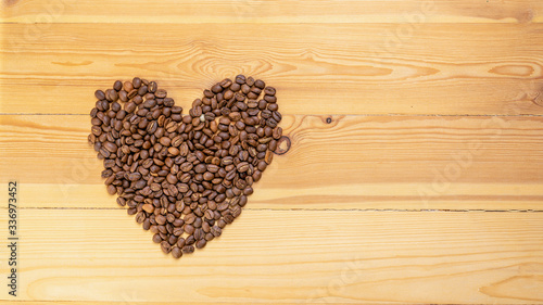 Roasted coffee beans shaped like hearts on a wooden table