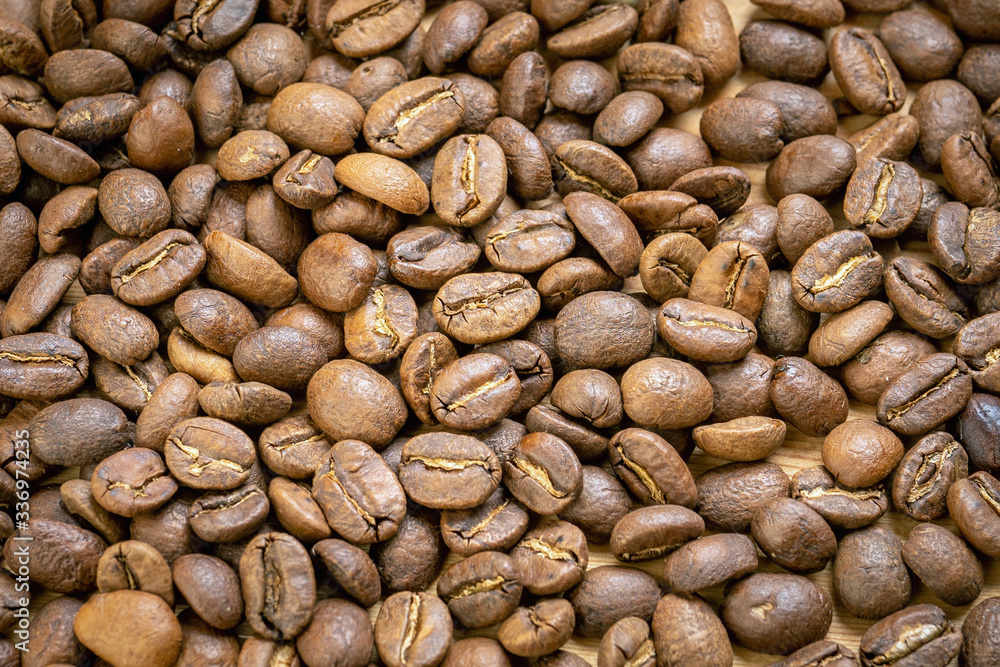 Roasted coffee beans randomly dumped on a wooden table-Close up Roasted coffee beans randomly dumped on a wooden table-Close up