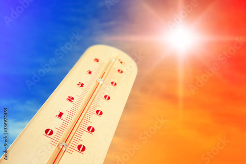 Weather thermometer with high temperature and color sky on background, space for text photo