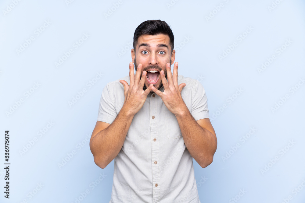 Young handsome man with beard over isolated blue background with surprise facial expression Young handsome man with beard over isolated blue background with surprise facial expression