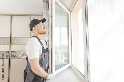 Worker in installing white plastic upvc window on house