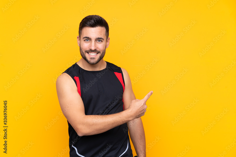 Man over isolated yellow background playing tennis and pointing to the lateral Man over isolated yellow background playing tennis and pointing to the lateral