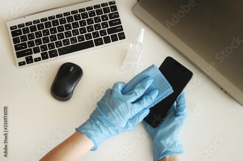 Sanitazing smartphone at workplace at home by desinfactant. Preventing disease photo