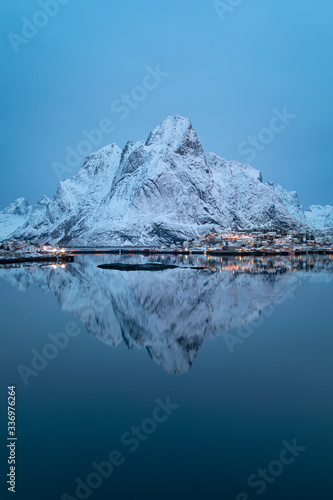 Lonely mountain perfectly reflected in cold, calm waters of northern fjord