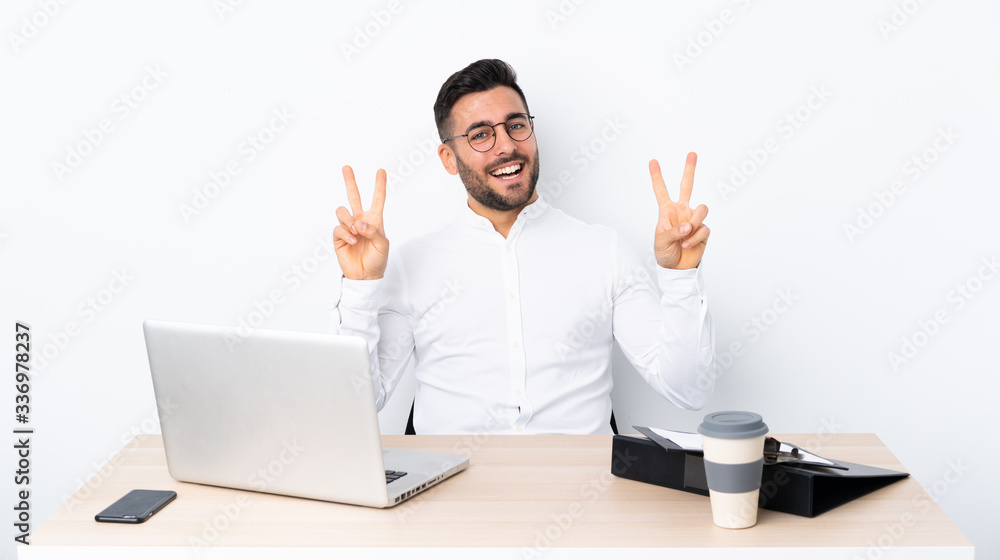 Young businessman in a workplace showing victory sign with both hands Young businessman in a workplace showing victory sign with both hands